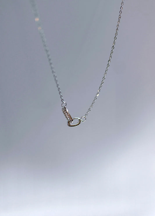 Collar de cadena fina con dije ovalado, bisutería de diseño exclusivo Mykoani sobre fondo gris.