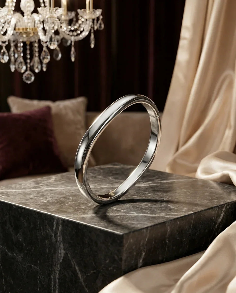 Brazalete de bisutería fina plateado sobre mármol negro, fondo elegante con cortinas y candelabro, MYKOANI.