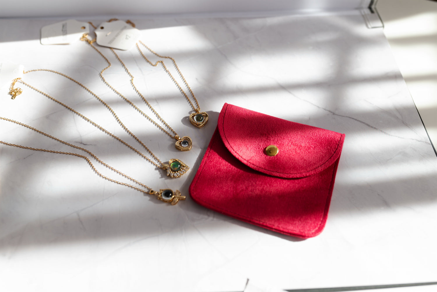 Collares de alta bisutería MYKOANI con estuche rojo sobre seda y pétalos rojos, novedades.