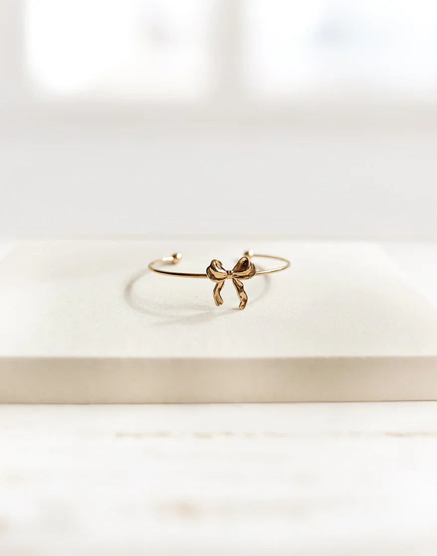 Pulsera de alta bisutería dorada con lazo, diseño exclusivo MYKOANI sobre fondo claro.