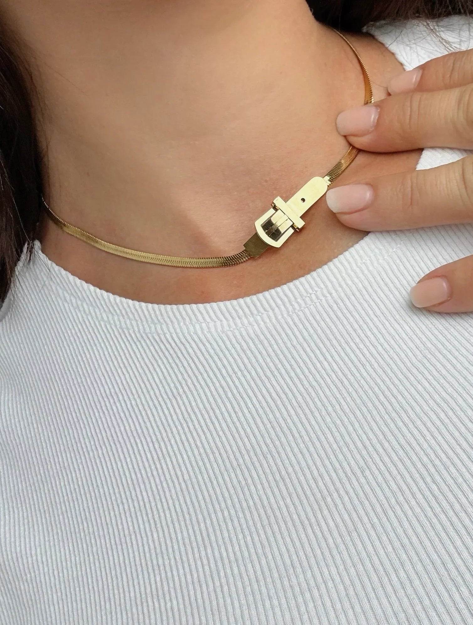 Collar dorado de diseño exclusivo Mykoani con cierre original sobre cuello en blusa blanca.