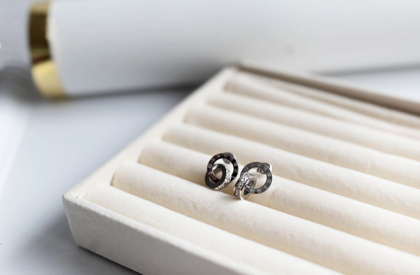 Aretes de bisutería fina MYKOANI en estuche beige, diseño exclusivo y detalles elegantes.