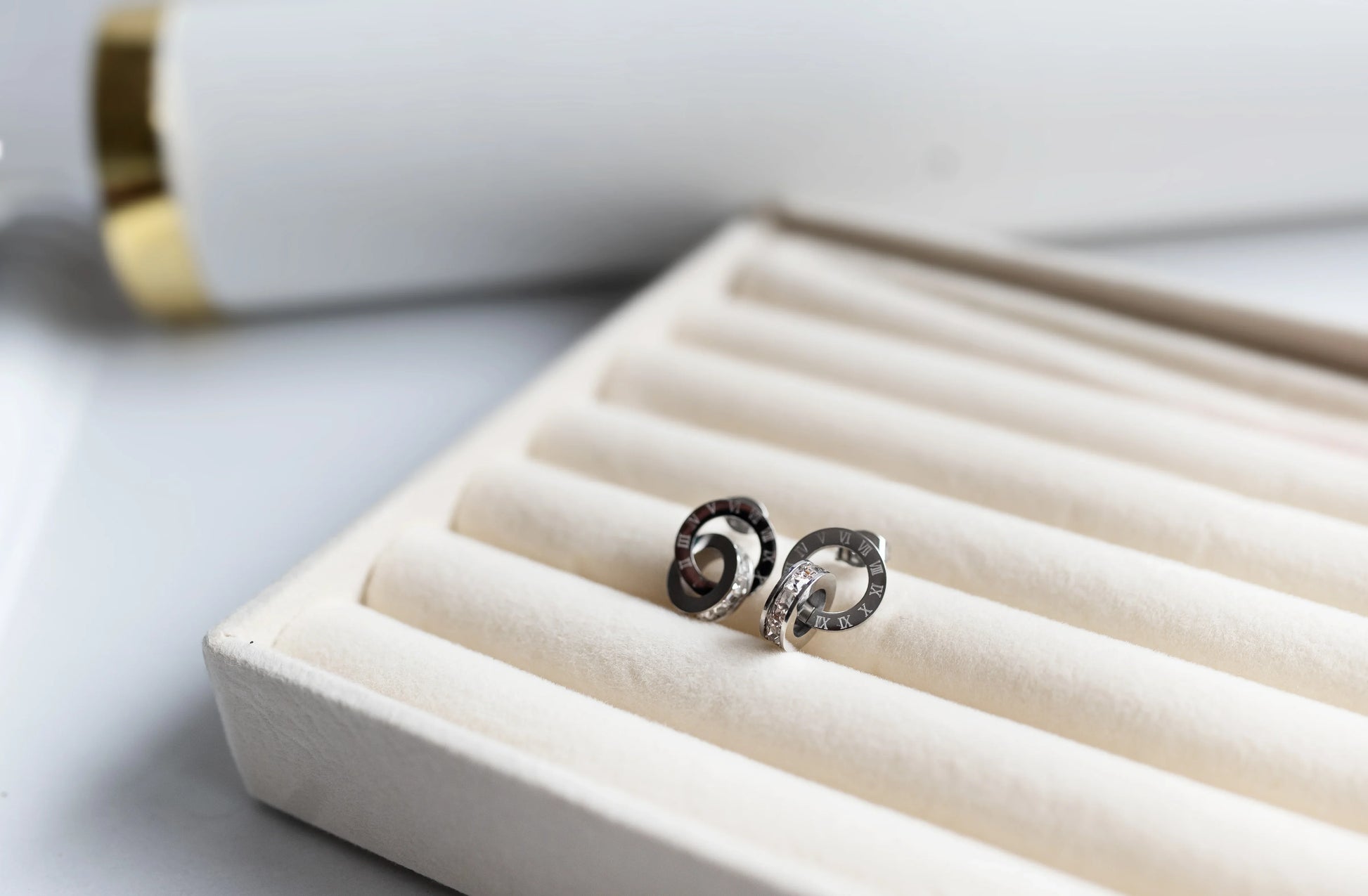 Aretes de bisutería fina MYKOANI en estuche beige, diseño exclusivo y detalles elegantes.