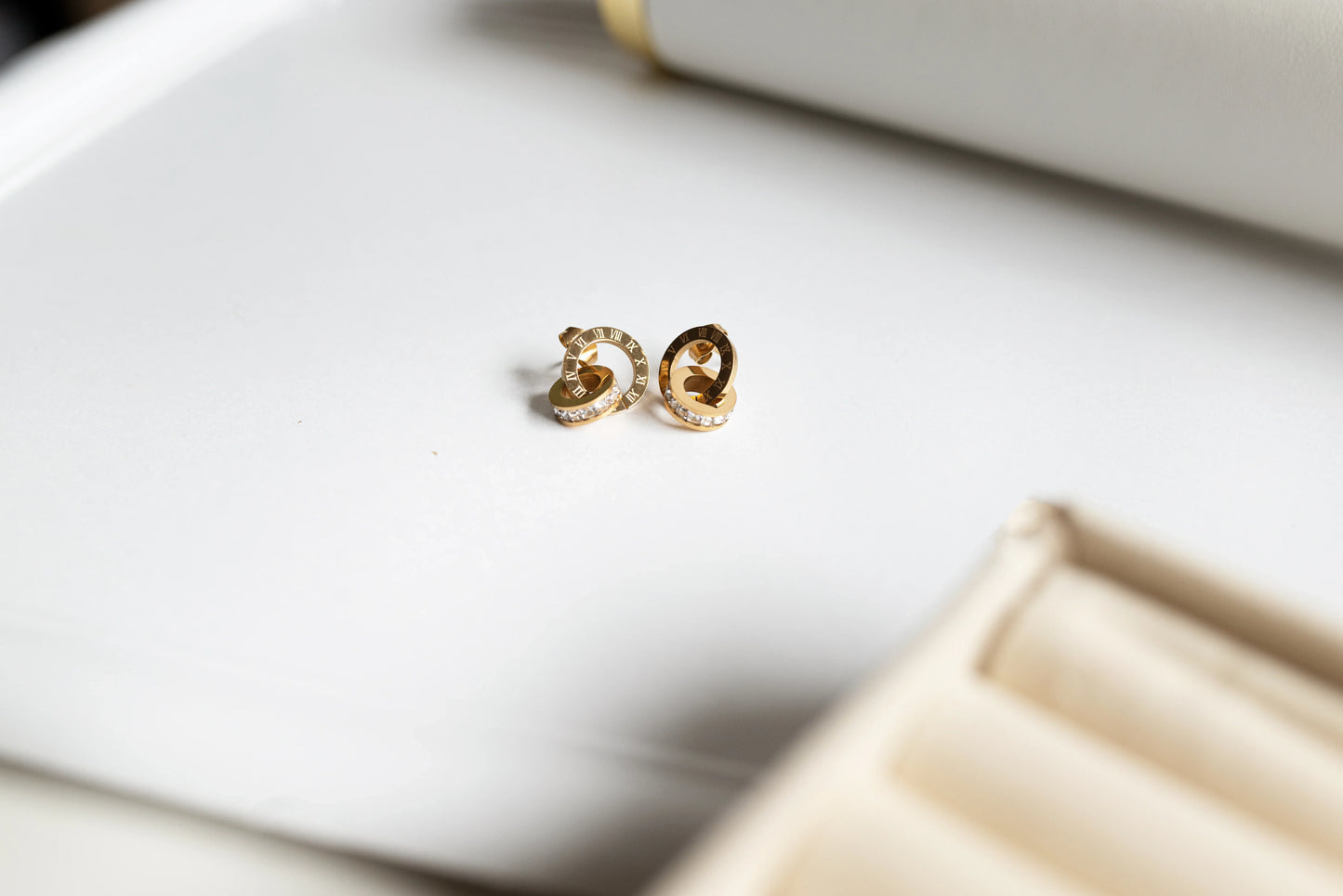 Aretes de bisutería fina dorados con detalles brillantes sobre fondo blanco, MYKOANI