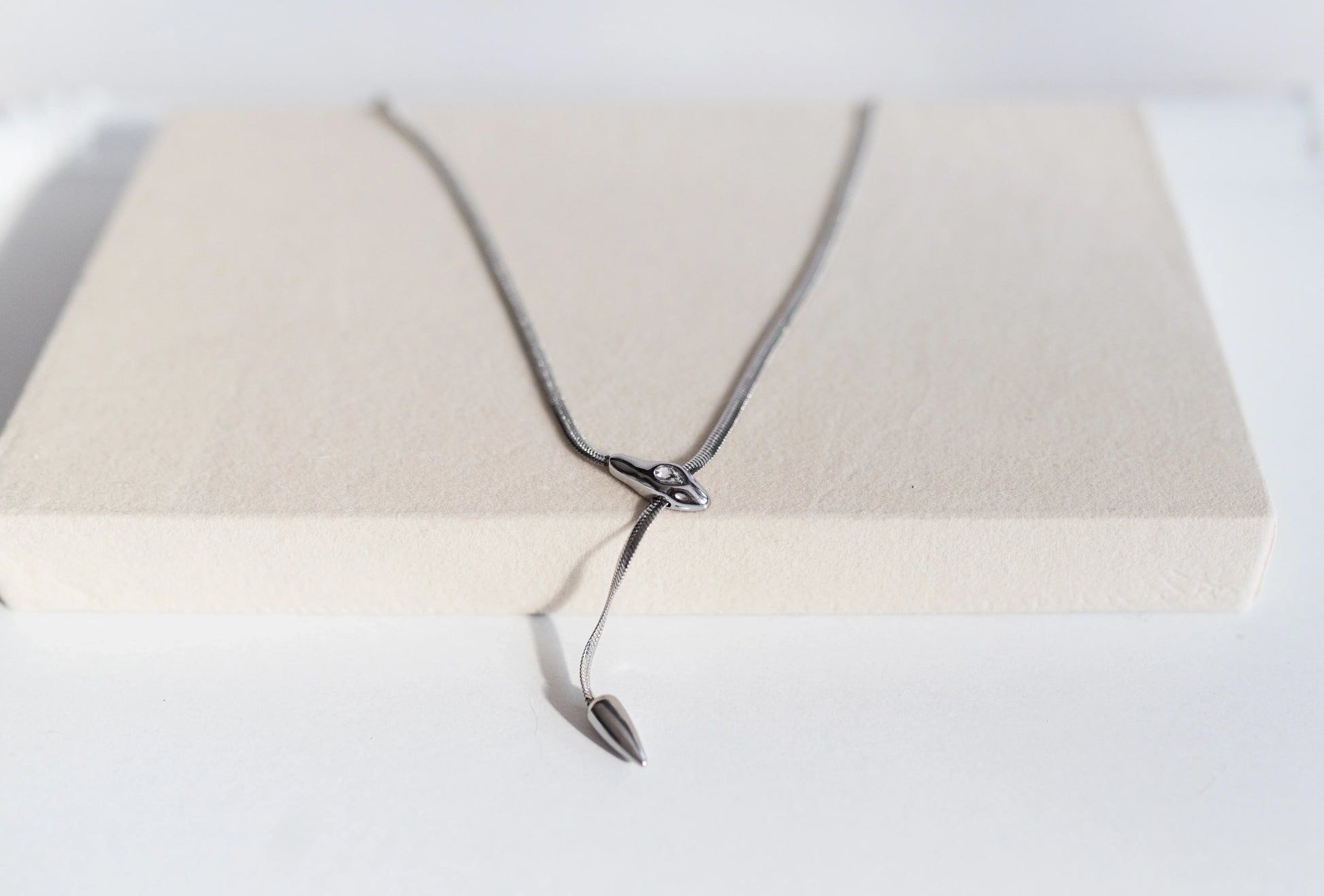 Collar de diseño exclusivo MYKOANI en plata, estilo moderno, sobre fondo beige elegante.