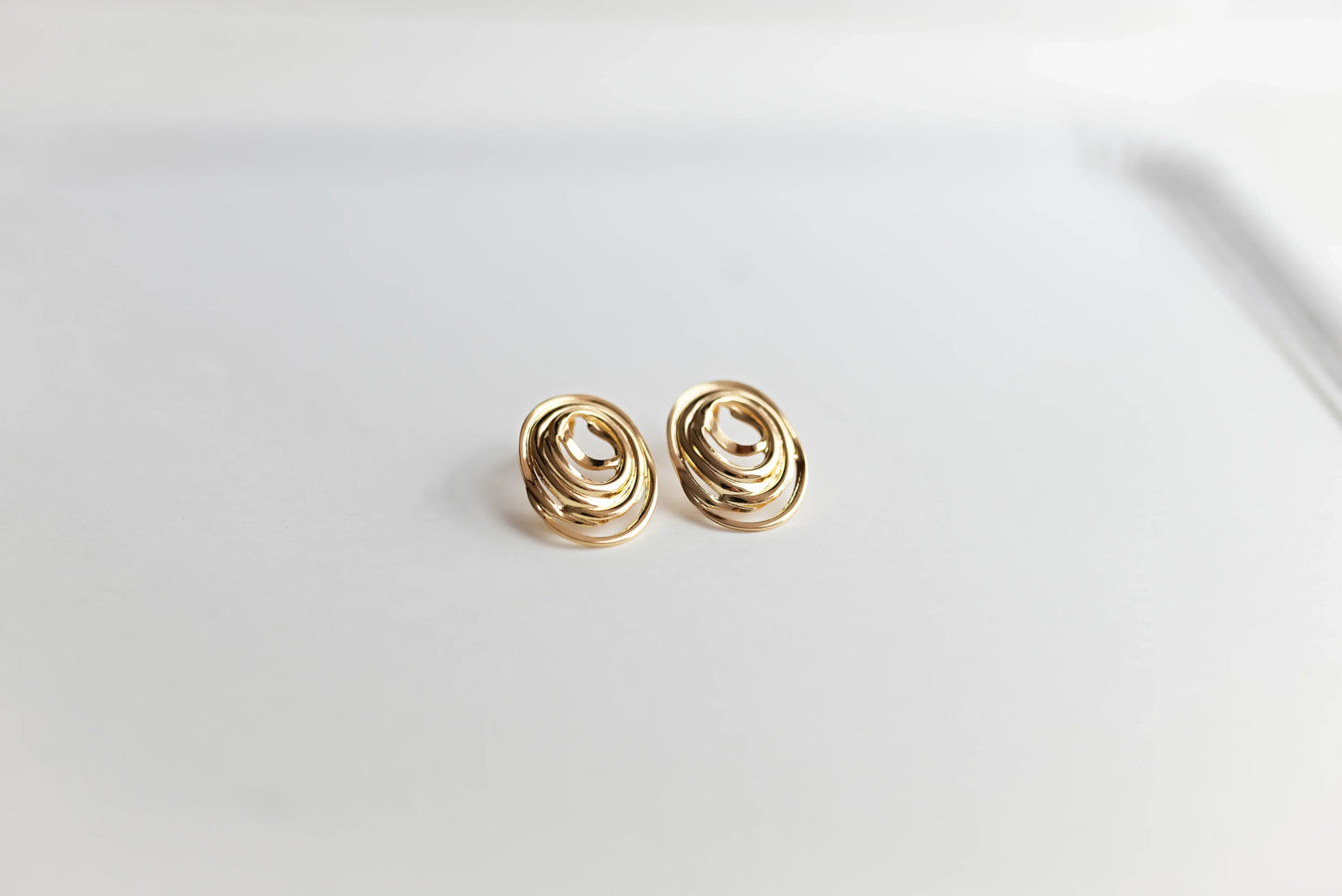 Pendientes ovalados dorados de bisutería fina MYKOANI sobre fondo blanco minimalista