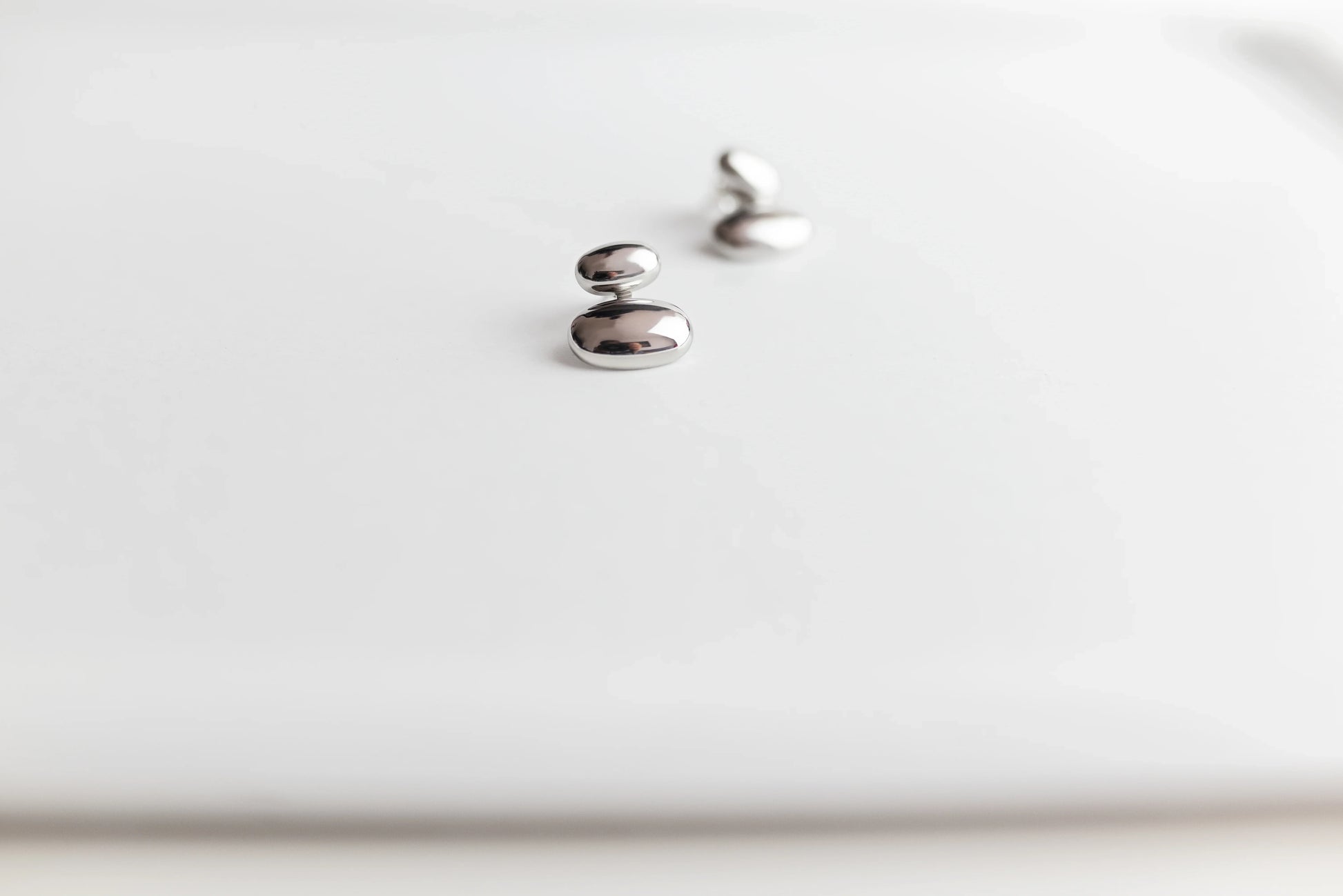 Pendientes de bisutería fina MYKOANI plateados de diseño minimalista sobre fondo blanco