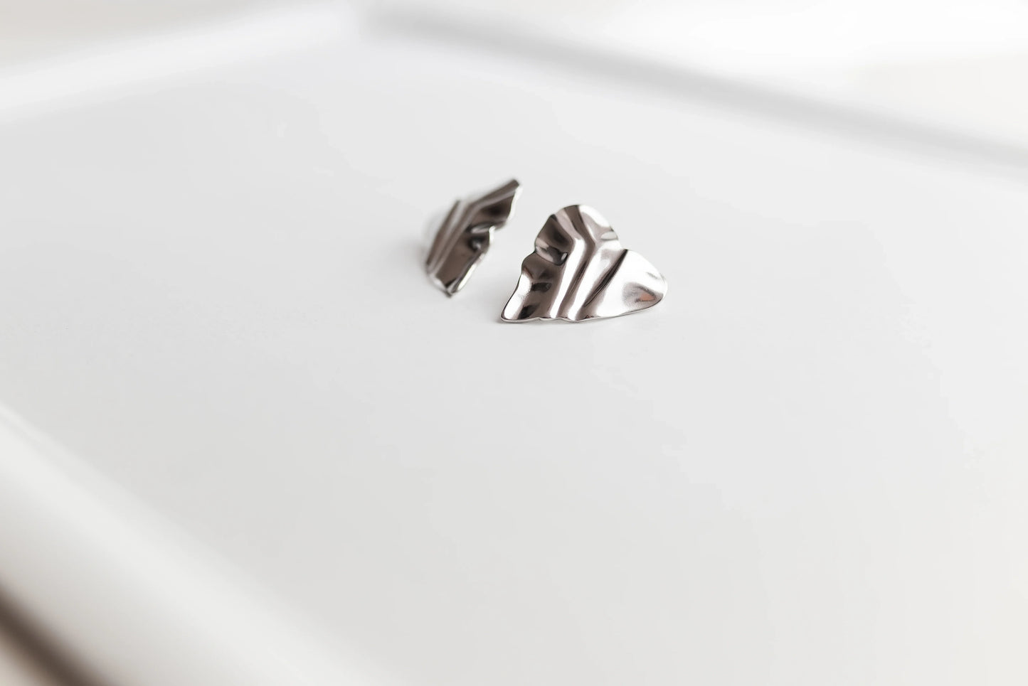 Pendientes de alta bisutería MYKOANI, diseño exclusivo plata arrugada sobre fondo blanco.