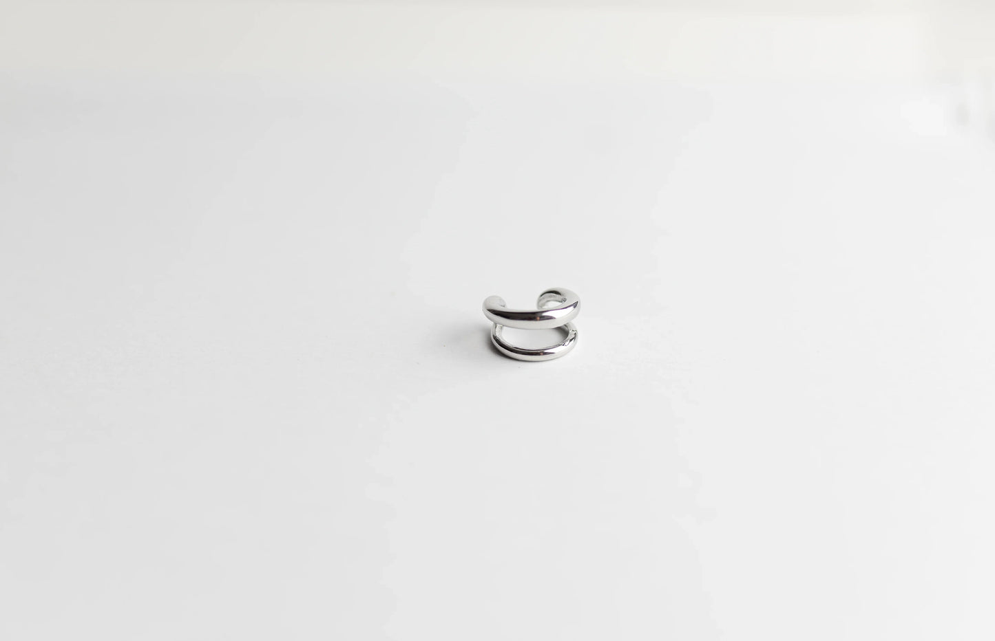 Ear cuff plateado de diseño minimalista, alta bisutería exclusiva MYKOANI sobre fondo blanco
